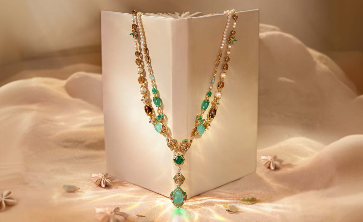 Zoya Rasika Serene Heart Necklace draped over a book in sand